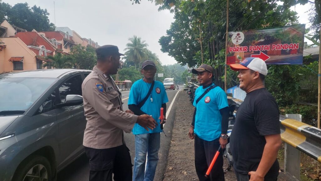 Bripka Eko dari Polsek Carita Berdiskusi dengan Petugas Parkir tentang Keselamatan Penyeberangan Pengunjung Pantai 10 WhatsApp Image 2024 06 16 at 17.38.31